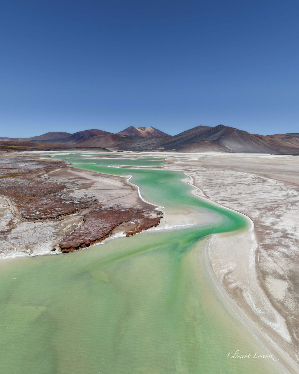 Piedras Rojas Atacama Desert Aerial shot of the Aguas Calientes salted flat where we can see the famous red rocks or Piedras Rojas. Close to the rocks we can see cristal emerald water. The place is surrounded by volcans.