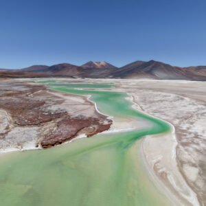 View of Piedras Rojas, a striking red rock formation in the Atacama Desert, Chile, contrasting with the surrounding salt flats and mountains.