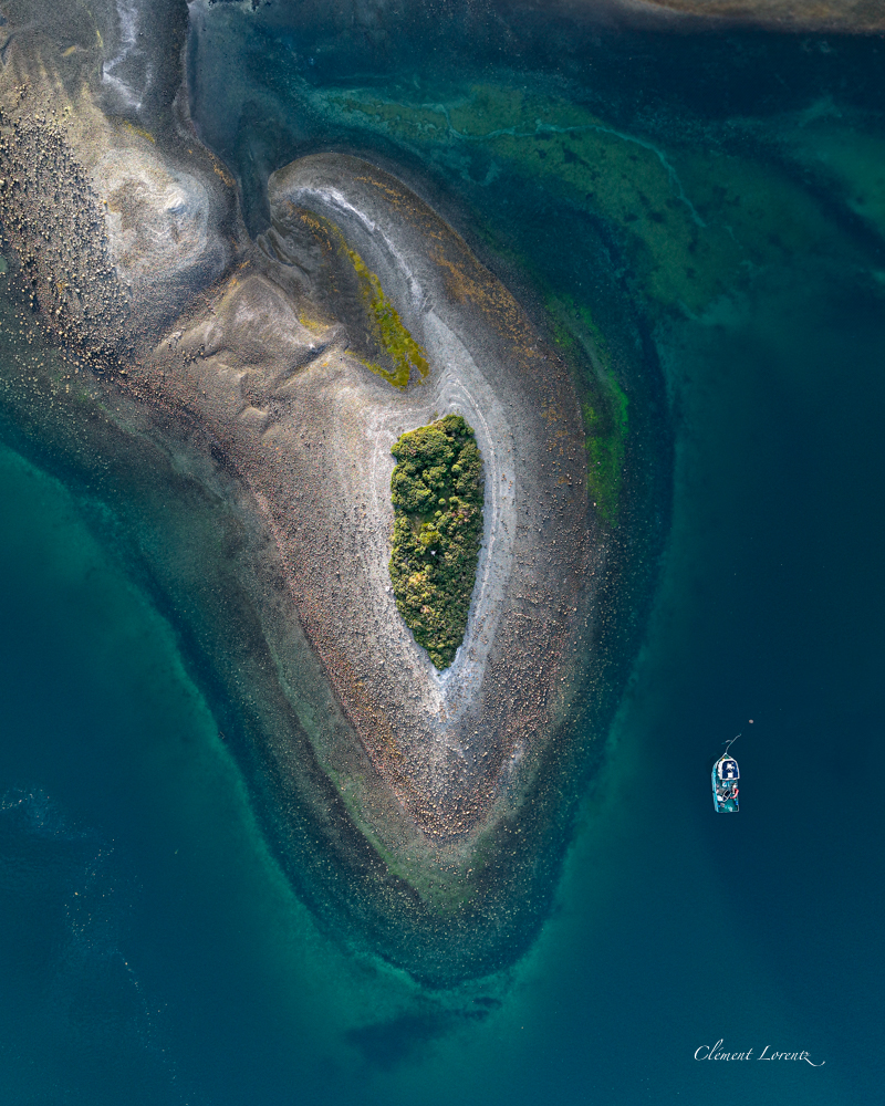 Fjord Chili Hornopiren Aerial view of a small green peninsula near Hornopirén, Chile, with a boat anchored nearby in the clear Patagonian waters.