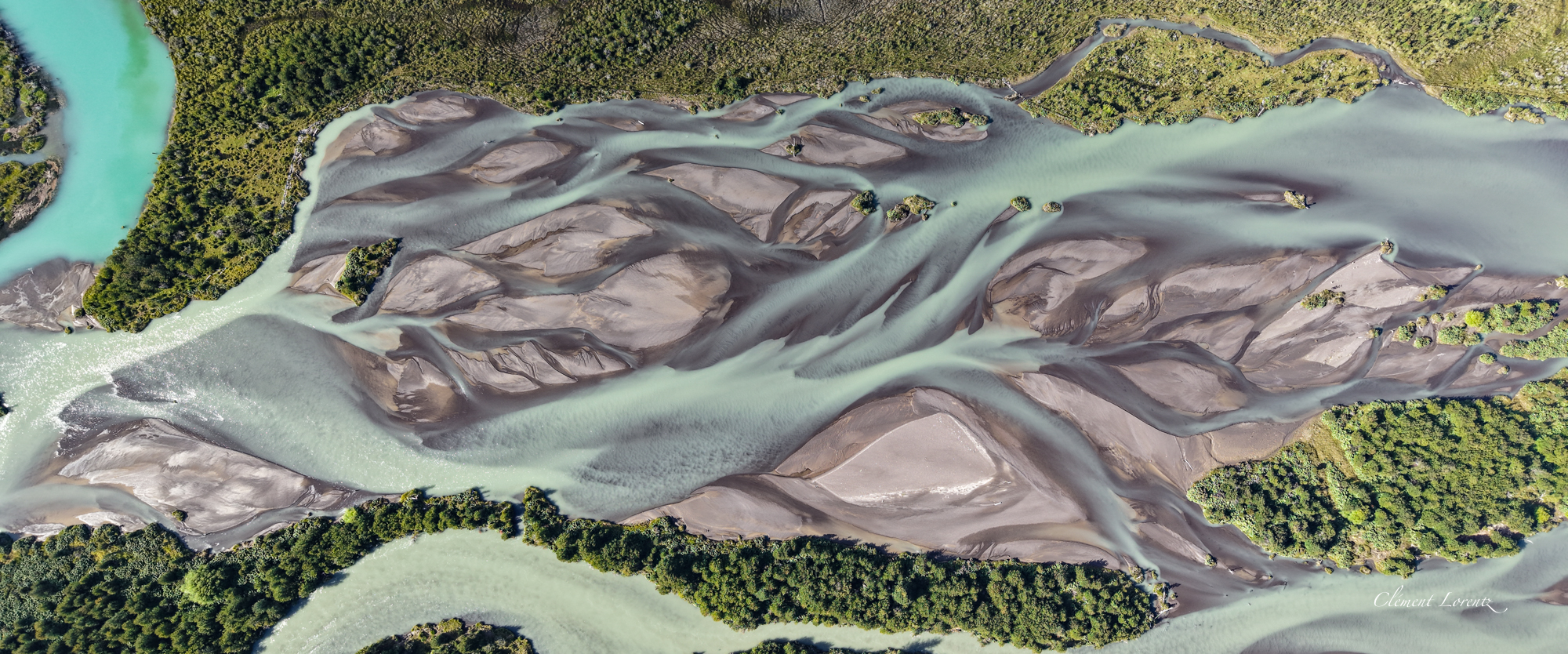 Riviere Carretera Austral Aerial view of a braided river along the Carretera Austral in Patagonia, Chile, showcasing multiple intertwining channels and surrounding lush landscapes.